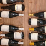 A wooden cabinet with several bottles of wine in it.