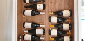 A wooden cabinet with several bottles of wine in it.