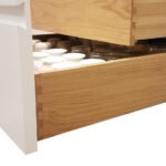 A wooden Cabinet drawer with jars and mugs in it.